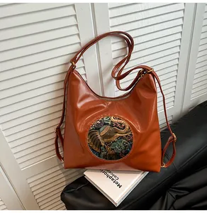 Detail of retro dark brown hobo bag featuring elephant embroidery and textured PU leather