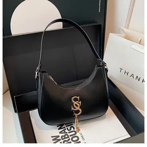 Détail du sac hobo noir avec ferrures dorées dans une boîte cadeau élégante