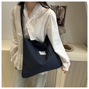 Detailaufnahme der dunkelblauen Denim-Tragetasche mit Kordelzug und weißem Webeetikett