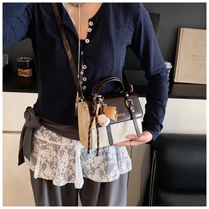 Detail of vintage bicolor crossbody bag with metal lock and baseball themed pendants