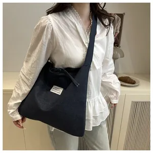 Detail einer großen blauen Canvas-Tasche mit modischem Aufnäher und Kordelzugverschluss