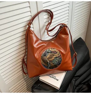Close-up of brown faux leather tote bag with an artistic elephant embroidery detail