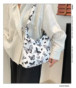 Dettaglio di una borsa a spalla bianca con stampe di farfalle nere indossata da modella