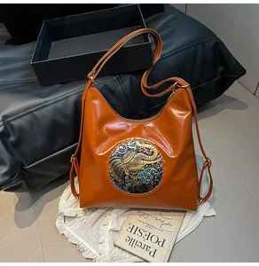 Close-up of caramel brown leather bag featuring an elephant embossed floral emblem