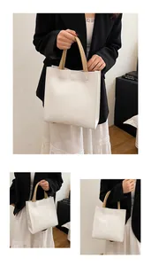 Close-up of white vertical tote bag featuring khaki dual handles and minimalist texture
