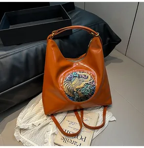 Detail of caramel orange faux leather bag with ethnic elephant embossed circular emblem
