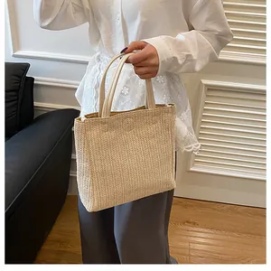 Détail d'un sac cabas en paille tressée avec poignées en cuir crème et texture en V