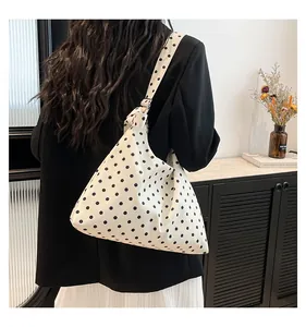 Dettaglio tracolla larga regolabile su borsa hobo in tela bianca a pois neri casual