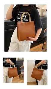Detail of caramel tote bag with contrast stitching and cream-colored top handles