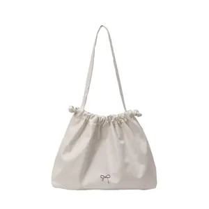 Minimalist beige pleated shoulder tote bag with silver bow accent and drawstring closure