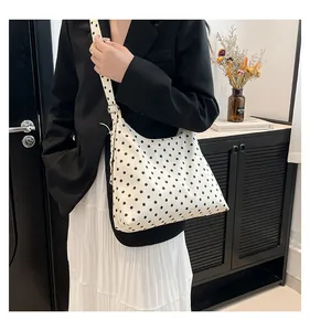Borsa a tracolla a pois indossata da una modella in un interno dallo stile minimal