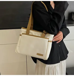 Detail showing the side view of the cream canvas tote bag with brown straps on a model