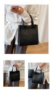 Close-up of a black matte vertical tote bag featuring minimalist handles and magnetic clasp