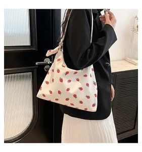 Dettaglio borsa a spalla con stampe di fragole rosse su tessuto di tela bianca resistente