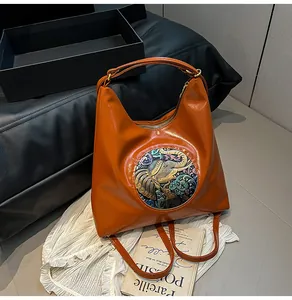 Detail of orange tote bag showing artistic elephant relief and shiny leather texture