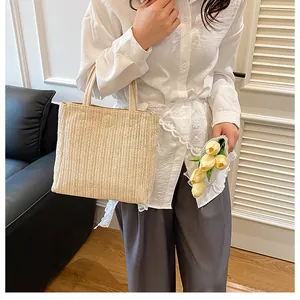 Détail du sac cabas en paille tissée avec poignées épaisses et motif à chevrons de plage