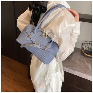 Détail du sac à main bleu clair avec texture tissée et finitions métalliques dorées