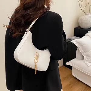 Sac sous le bras blanc en forme de croissant avec pompon doré et cuir lisse