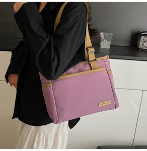 Detail of purple canvas tote bag with adjustable strap and fashion label on the front