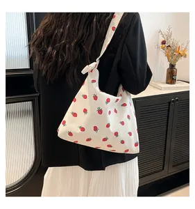 Modella che indossa una borsa a tracolla in tela con stampa di fragole rosse su bianco