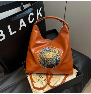 Detail of caramel leather tote bag with ethnic elephant embroidery in luxury gift box