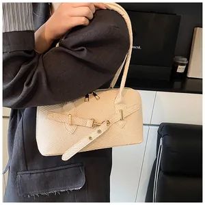 Détail du sac à main beige montrant le cuir texturé et la boucle en métal doré