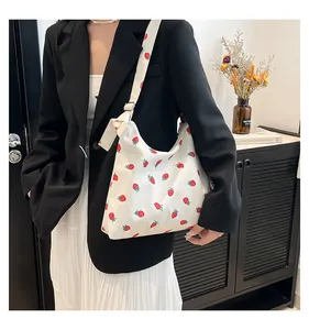 Dettaglio della borsa shopper bianca con stampe di fragole rosse e tracolla larga