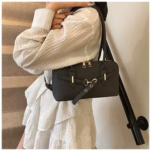 Gros plan d'un sac à bandoulière noir tressé avec détails dorés porté par un mannequin