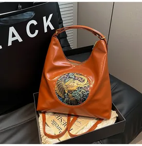 Close-up of brown leather bag with vintage elephant emblem inside a black gift box