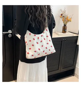 Dettaglio di una borsa a tracolla bianca con stampa a fragole in un contesto lifestyle