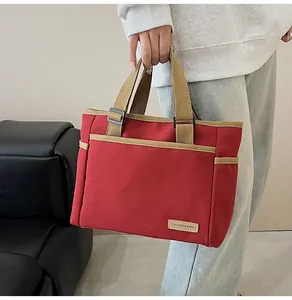 Close-up of red canvas tote bag with khaki straps and leather fashion label detail