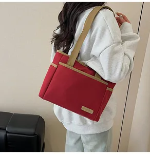 Detail of red canvas tote bag with khaki straps and fashion leather label on side pocket