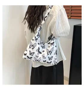Borsa tote in tela con stampa a farfalla nera indossata a spalla, stile casual e morbido