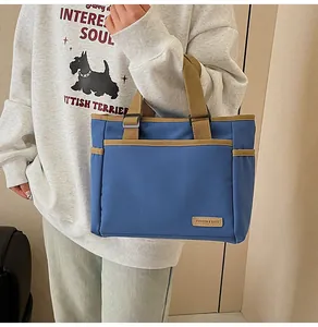 Detail of blue canvas tote bag featuring front utility pockets and contrasting straps