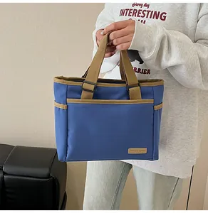 Detail of navy canvas tote bag with contrast brown trim and leather logo patch