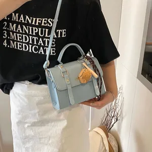 Fashionable light blue PU leather handbag with vertical buckles and baseball charm