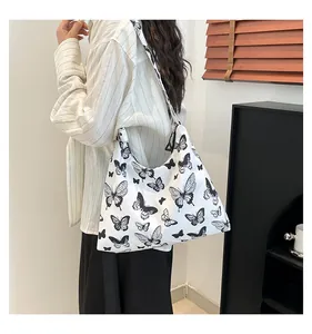 Vista laterale della borsa tote con fiori e farfalle indossata da una modella in stanza