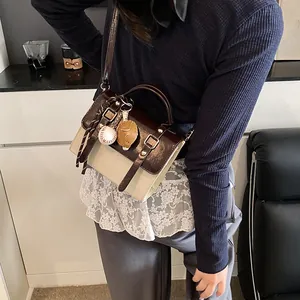 Retro contrast color crossbody bag with handle and baseball charm in lifestyle setting