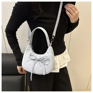 Detalle del bolso de media luna azul claro con lazo elegante y correa extraíble