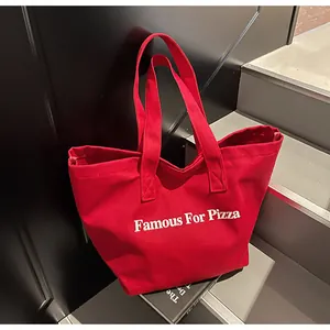 Detailansicht der roten Canvas-Tragetasche mit 'Famous For Pizza' Aufdruck auf Treppen