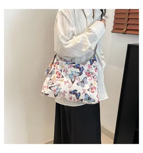 Dettaglio di farfalle colorate su una borsa hobo capiente in tela bianca con tracolla larga