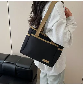Detail of black canvas tote bag with brown straps and branded fashion label tag
