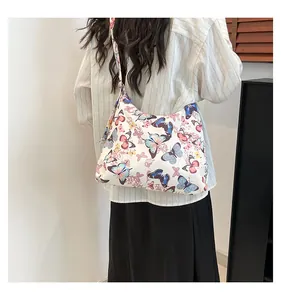 Vista a spalla di una grande borsa tote in tela con stampa a farfalla e cerniera