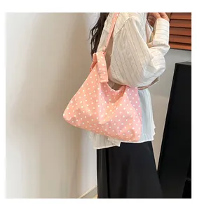 Dettaglio della grande borsa tote in tela rosa a pois con ampia tracolla e stile casual