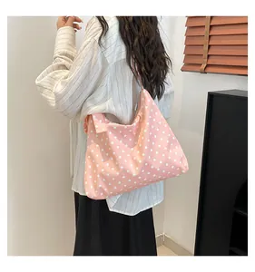 Dettaglio della borsa tote rosa a pois bianchi in nylon resistente e spaziosa