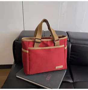 Detailed close-up of red canvas tote bag with khaki straps on a black sofa
