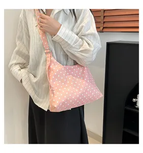 Dettaglio della borsa a tracolla in nylon a pois rosa con tracolla regolabile su un modello