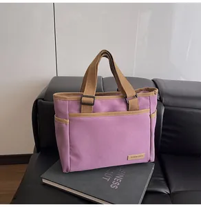 Detail of purple canvas tote bag with brown webbing handles on a stylish sofa