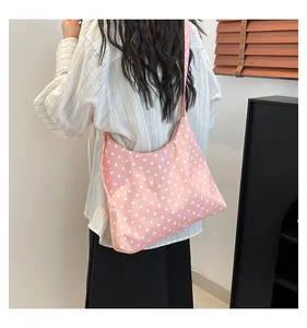 Grande borsa hobo in tela rosa a pois indossata a spalla, vista lifestyle