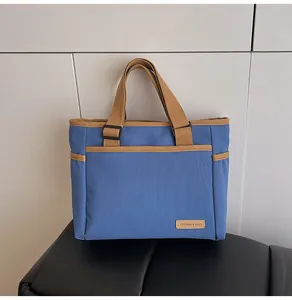 Detail view of navy canvas tote bag showing textured fabric and brown woven handles